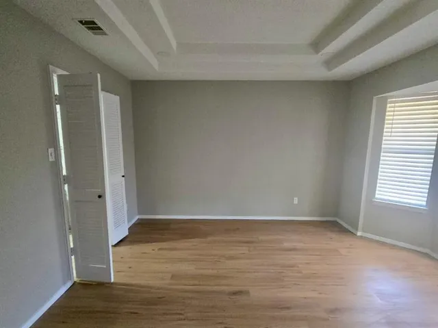 a view of an empty room with wooden floor and a window