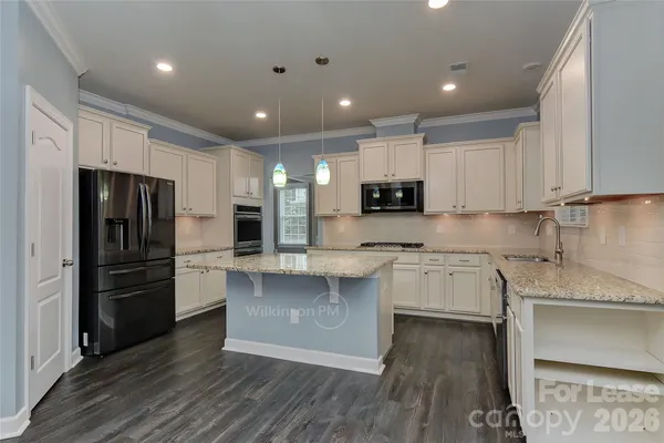 a kitchen with stainless steel appliances granite countertop a refrigerator a stove microwave and cabinets