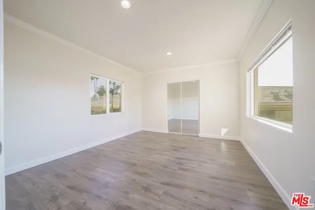 a view of an empty room with window and wooden floor
