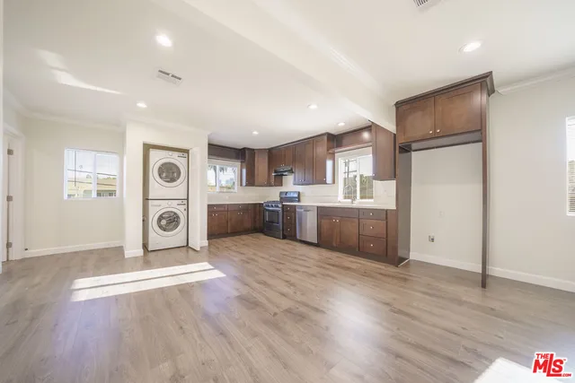 a large kitchen with stainless steel appliances granite countertop a refrigerator oven a sink dishwasher and a refrigerator with wooden floor