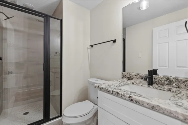 a bathroom with a granite countertop sink toilet and shower