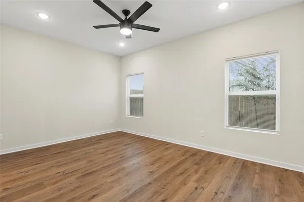 an empty room with wooden floor and windows