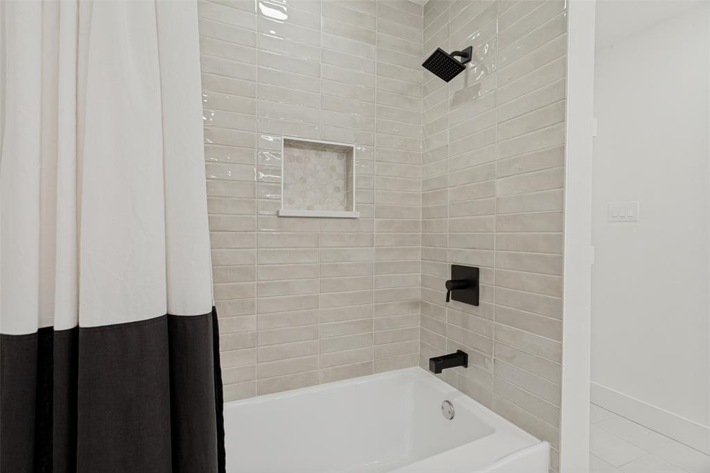 4316 Springbranch Drive Benbrook, TX 76116 - Photo 31 of 39 Bathtub shower with light grey horizontal subway tile surround, matte black shower fixtures, and a recessed tile niche