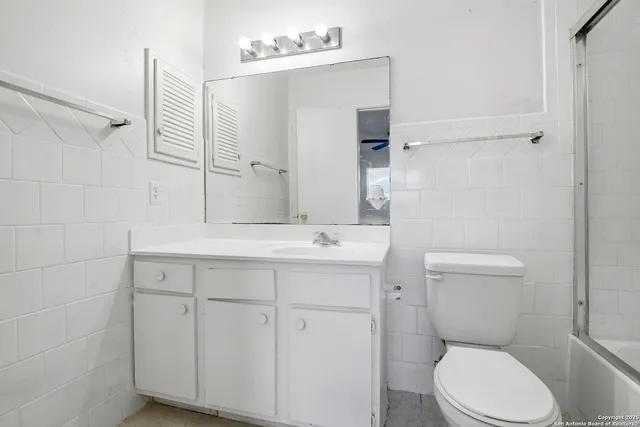a bathroom with a toilet a sink a mirror and vanity