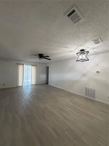 an empty room with wooden floor ceiling fan and windows