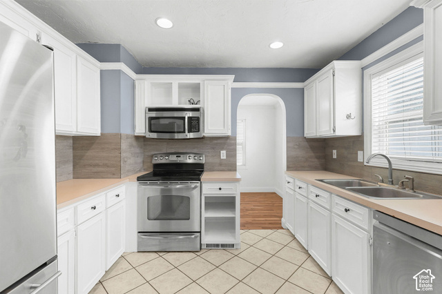 154 South State Street Morgan, UT 84050 - Photo 4 of 25 White cabinetry with dark hardware, stainless steel appliances, dual basin sink, light-toned countertops, and tile flooring