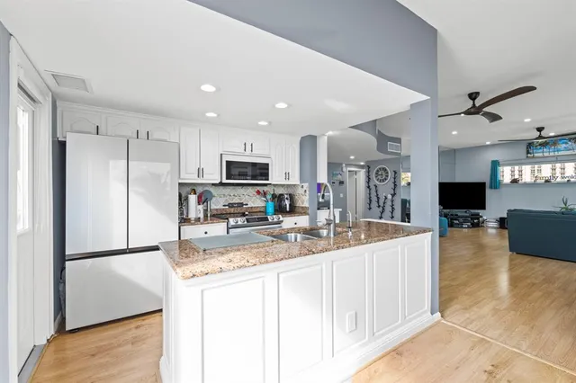 a kitchen with stainless steel appliances granite countertop a sink a stove and a wooden floors