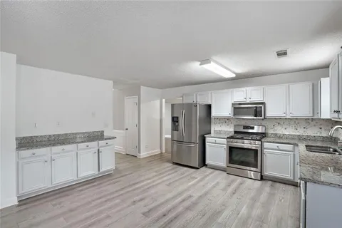 a kitchen with stainless steel appliances granite countertop a stove top oven a sink and a refrigerator