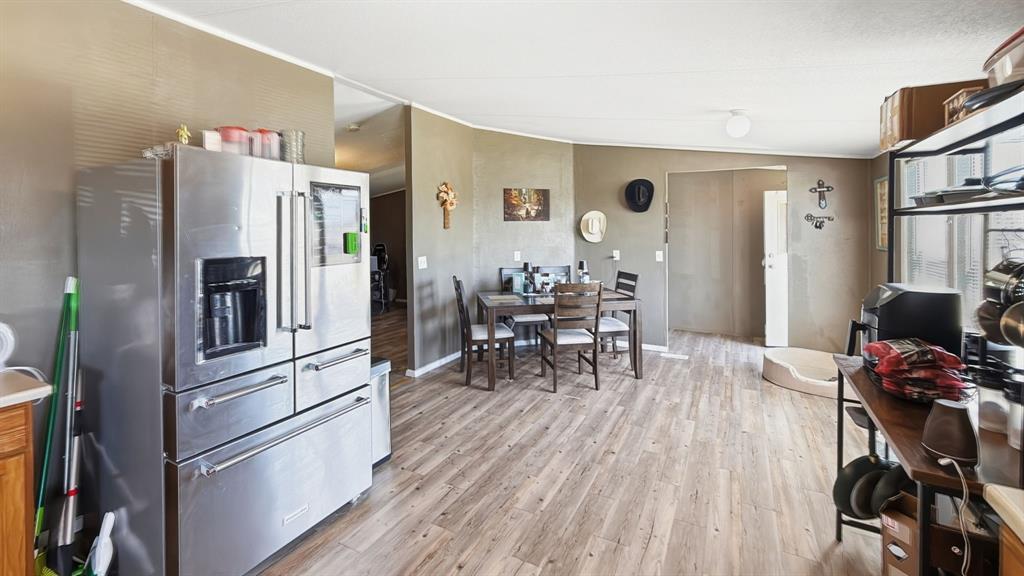185 Private Road 4437 Rhome, TX 76078 - Photo 13 of 28 Open-concept living area featuring wood-finish flooring throughout, a dining space, and a stainless steel French door refrigerator with a bottom freezer