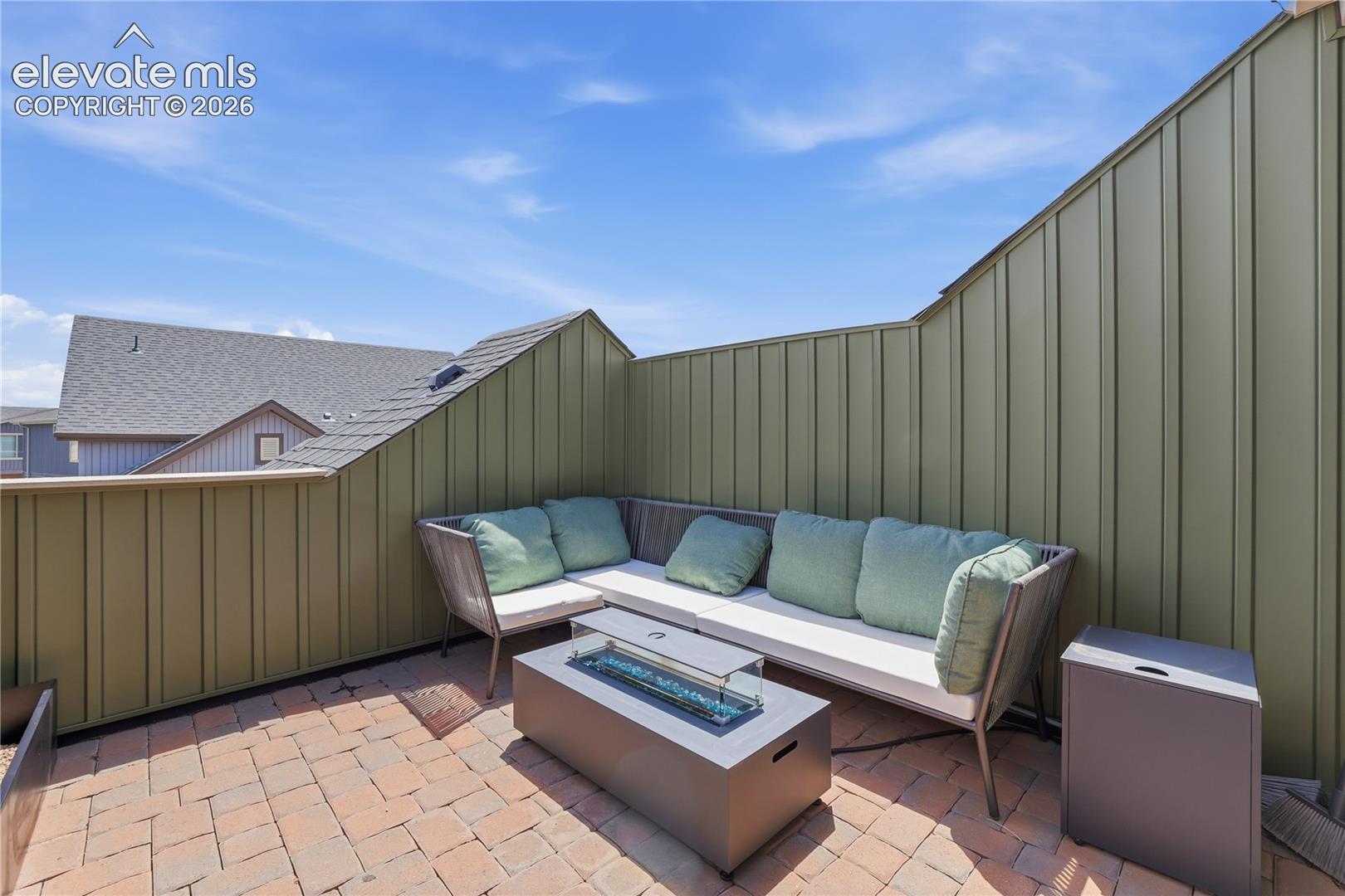 6008 Ashmore Road Colorado Springs, CO 80927 - Photo 41 of 48 Private rooftop patio featuring brick paver flooring, board-and-batten style privacy walls, and a built-in fire pit