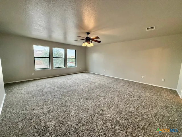 an empty room with a ceiling fan and windows
