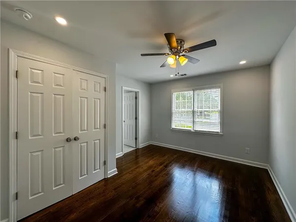 an empty room with wooden floor and windows with curtains