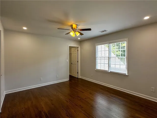 a view of an empty room with a window and wooden floor