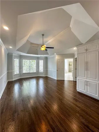 an empty room with wooden floor chandelier and windows