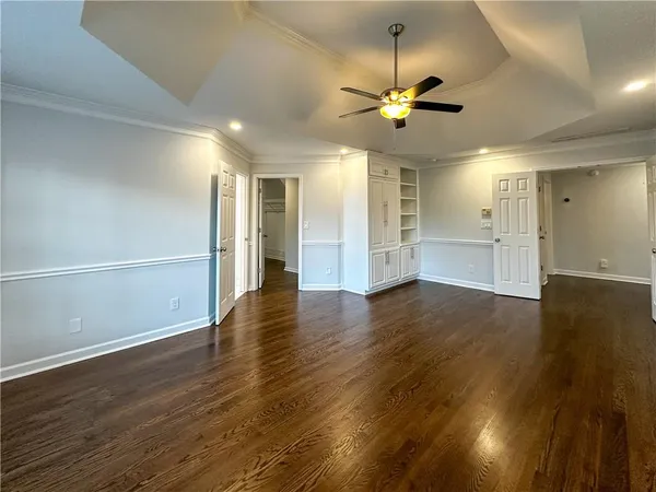 a view of an empty room with wooden floor and a ceiling fan