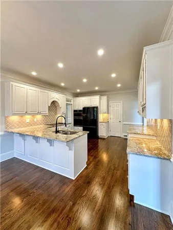 a large kitchen with granite countertop a large counter top stainless steel appliances and cabinets