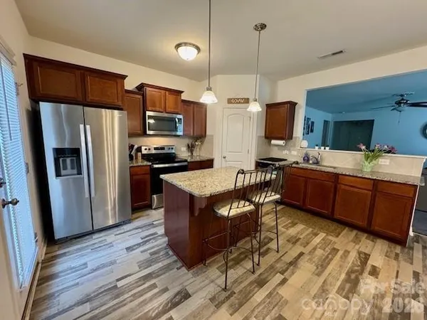 a kitchen with stainless steel appliances kitchen island granite countertop a refrigerator a stove top oven a sink and dishwasher