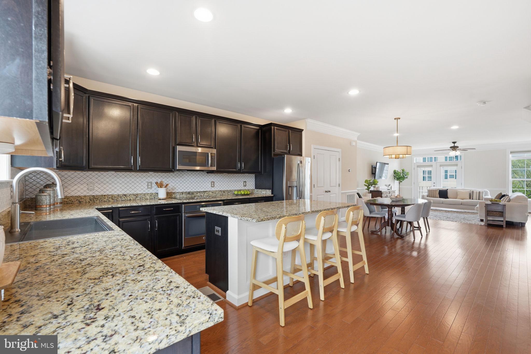 204 Miles Hawk Terrace Purcellville, VA 20132 - Photo 12 of 40 a kitchen with stainless steel appliances granite countertop a stove top oven a sink a dining table and chairs with wooden floor