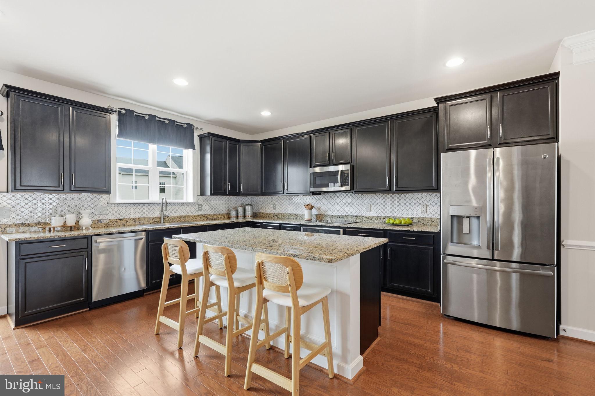 204 Miles Hawk Terrace Purcellville, VA 20132 - Photo 2 of 40 a kitchen with stainless steel appliances granite countertop a refrigerator a stove a sink a dining table and chairs