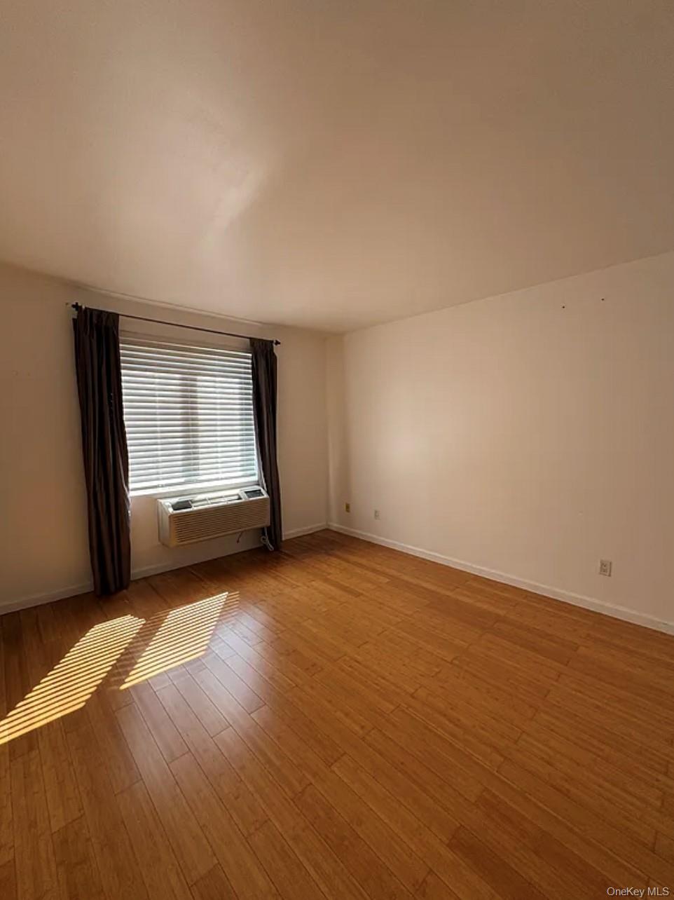 112-02 Northern Boulevard, Unit 6C Queens, NY 11368 - Photo 4 of 6 an empty room with wooden floor and windows