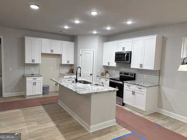 a kitchen with a sink stove top oven and refrigerator
