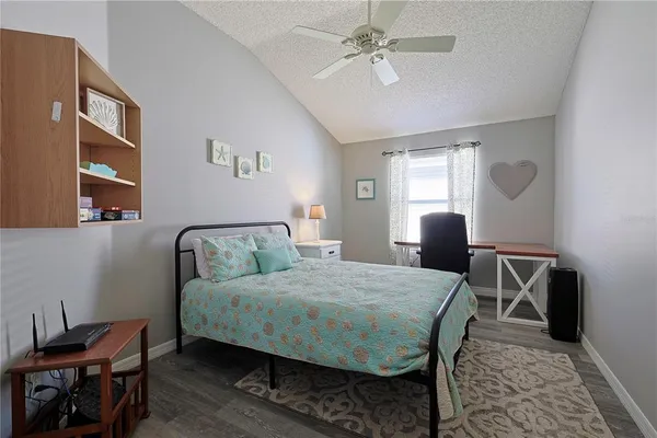 a bedroom with a bed a desk and chair with wooden floor