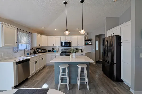 a kitchen with stainless steel appliances a dining table chairs sink and refrigerator