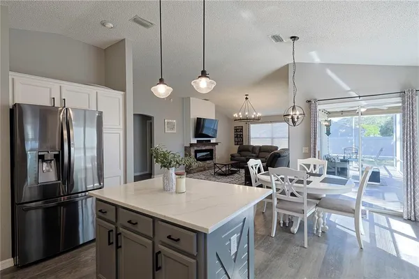 a kitchen with stainless steel appliances a dining table chairs a refrigerator and cabinets