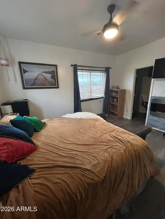 a bedroom with a bed a mirror on dresser and a wooden floor