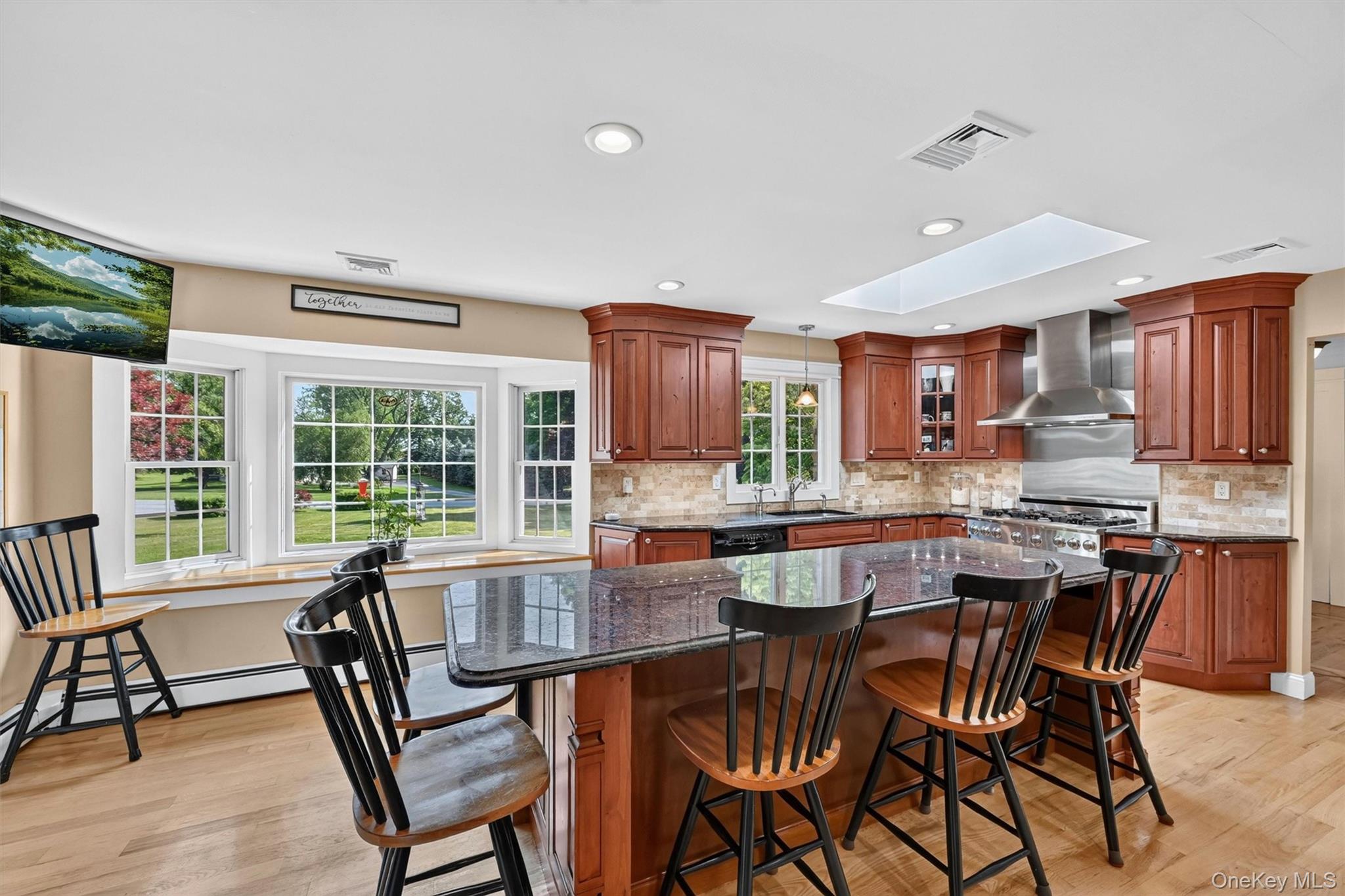 5 Hedges Road Warwick, NY 10990 - Photo 14 of 48 Natural light pours in through the skylight and large bay window, bringing warmth to the kitchen’s rich cabinetry, granite counters, and comfortable gathering space.