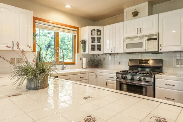 a kitchen with stainless steel appliances granite countertop a stove a sink and a microwave