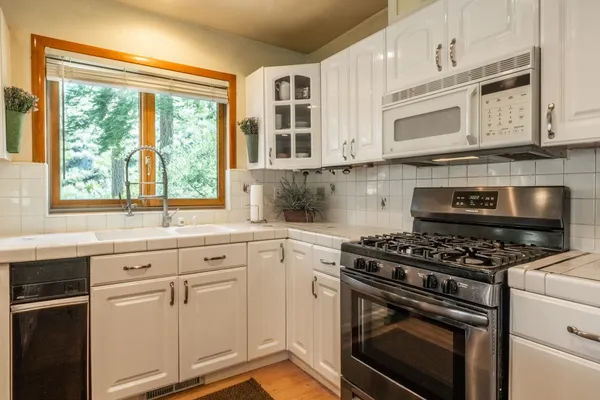 a kitchen with stainless steel appliances white cabinets and a stove top oven