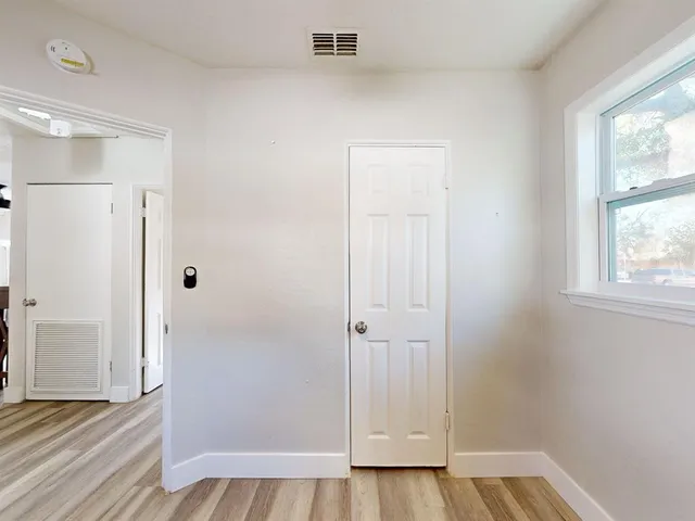 a view of an empty room with a window and wooden floor
