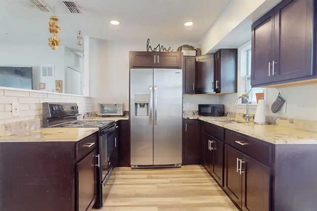 a kitchen with stainless steel appliances granite countertop a sink stove refrigerator and cabinets