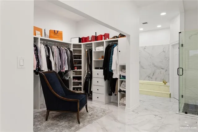 a view of walk in closet with clothes and shoes