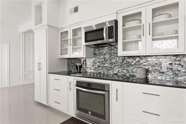 a kitchen with stainless steel appliances white cabinets and a stove top oven