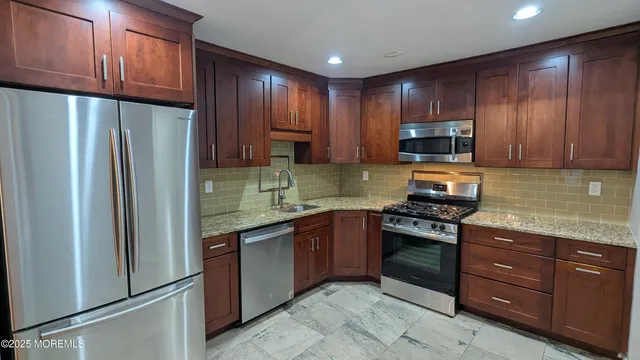 a kitchen with stainless steel appliances granite countertop a refrigerator stove a sink and dishwasher