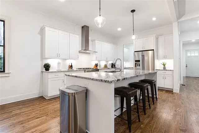 a kitchen with granite countertop wooden floors refrigerator dining table and chairs