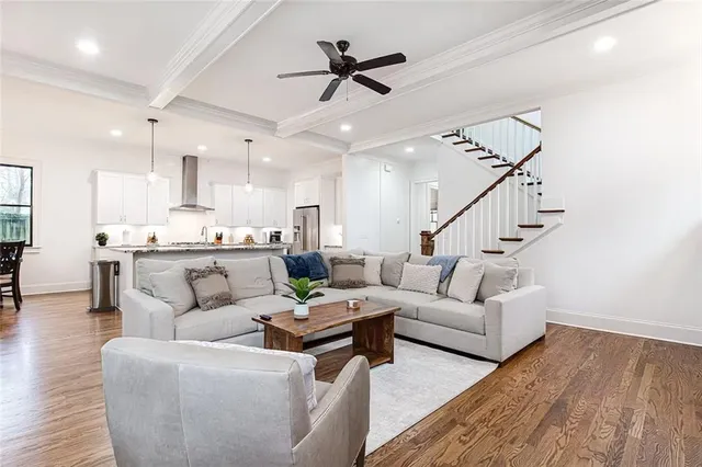 a living room with furniture kitchen view and a wooden floor