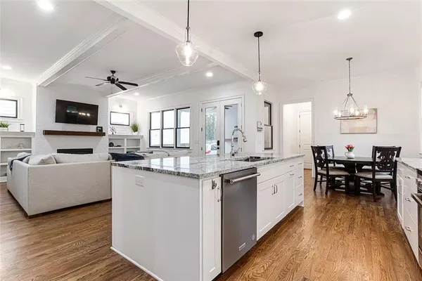 a kitchen with granite countertop a stove a sink a dining table and chairs with wooden floor
