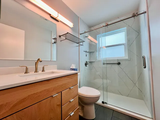 a bathroom with a granite countertop sink toilet a mirror and shower