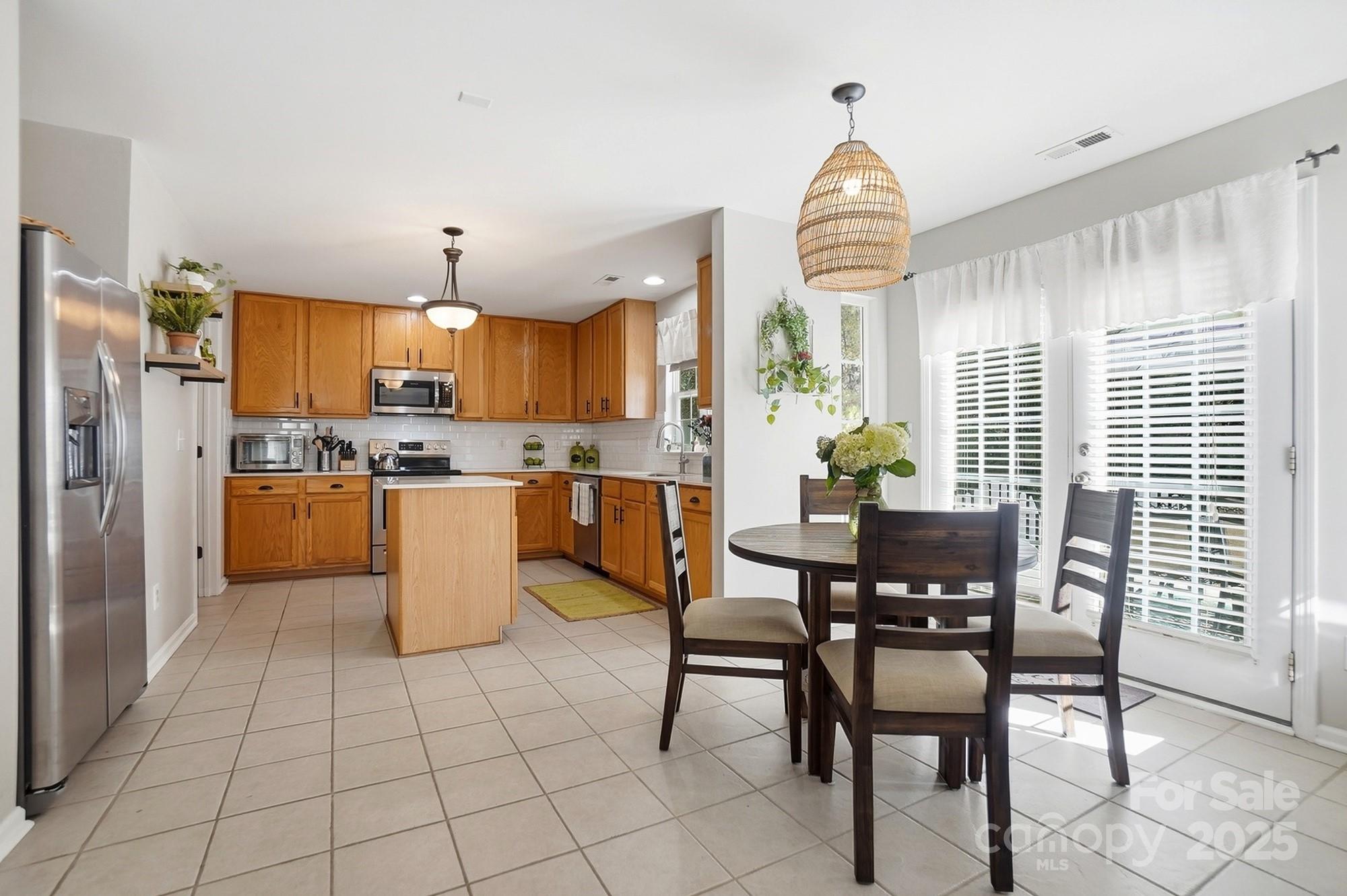 7200 Cascading Pines Drive Tega Cay, SC 29708 - Photo 12 of 39 a kitchen with stainless steel appliances granite countertop a stove a refrigerator a dining table and chairs