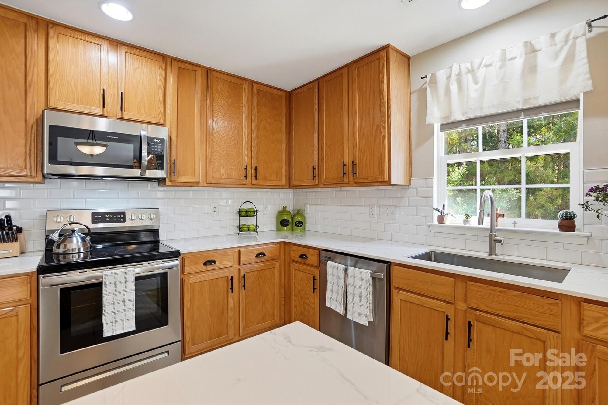 7200 Cascading Pines Drive Tega Cay, SC 29708 - Photo 17 of 39 a kitchen with stainless steel appliances granite countertop a sink a stove a microwave cabinets and a window