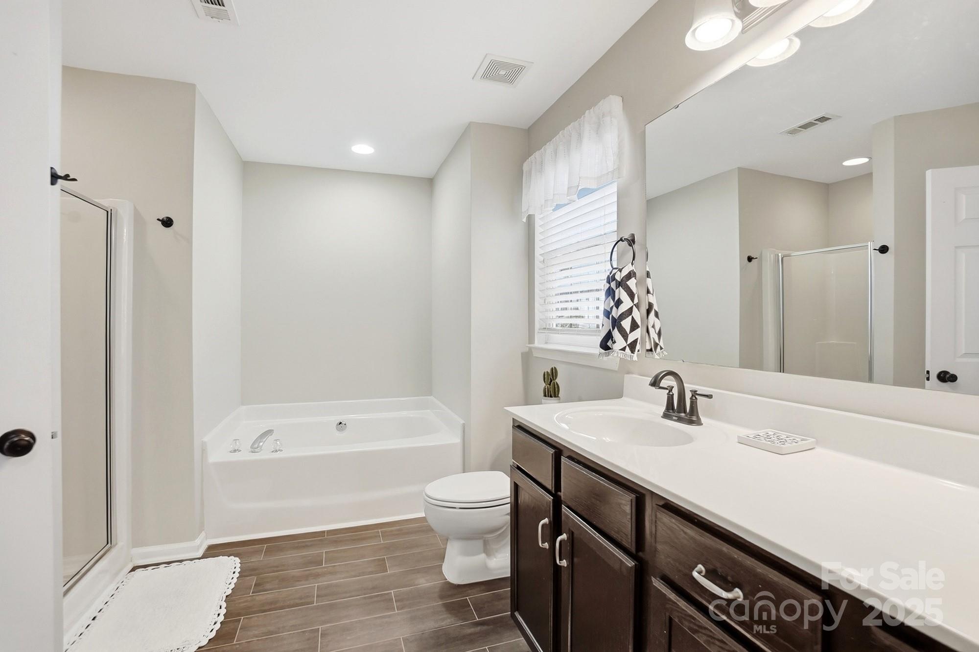 7200 Cascading Pines Drive Tega Cay, SC 29708 - Photo 24 of 39 a bathroom with a sink a toilet a tub and a large mirror