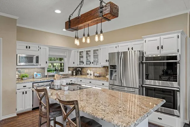 a kitchen with stainless steel appliances kitchen island granite countertop a dining table and chairs