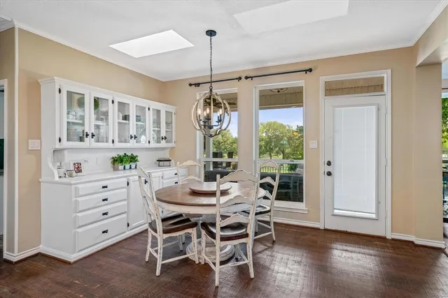 a dining room with wooden floor a chandelier a wooden table and chairs