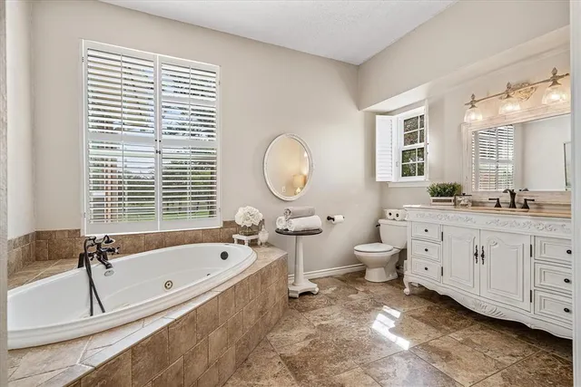a bathroom with a double vanity sink a large mirror a toilet and a bathtub