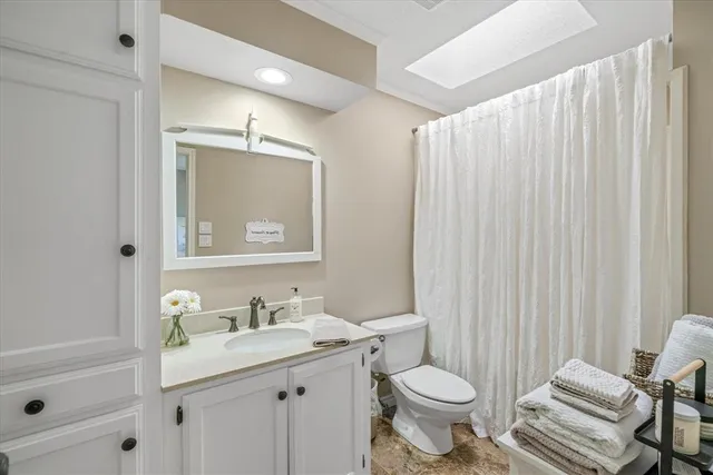 a bathroom with a granite countertop toilet sink and mirror