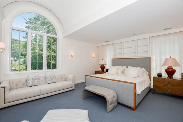 a bedroom with a bed couch and a large window