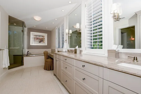 a bathroom with a granite countertop double vanity sink a bathtub and window